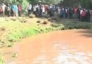 Student and locals stand along banks of river Narok as they await bodies of their colleagues to be retreived